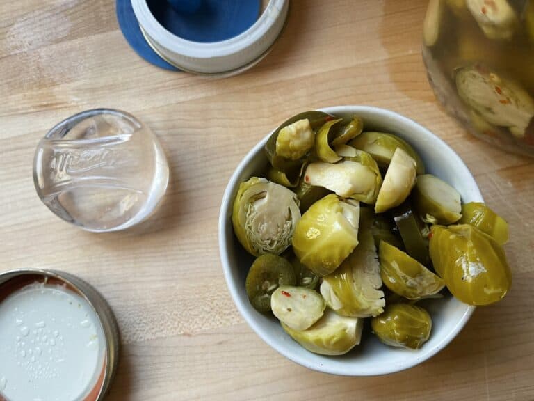 bowl of fermented brussels sprouts sitting next to a pickle pickle pebble and pickle pipe