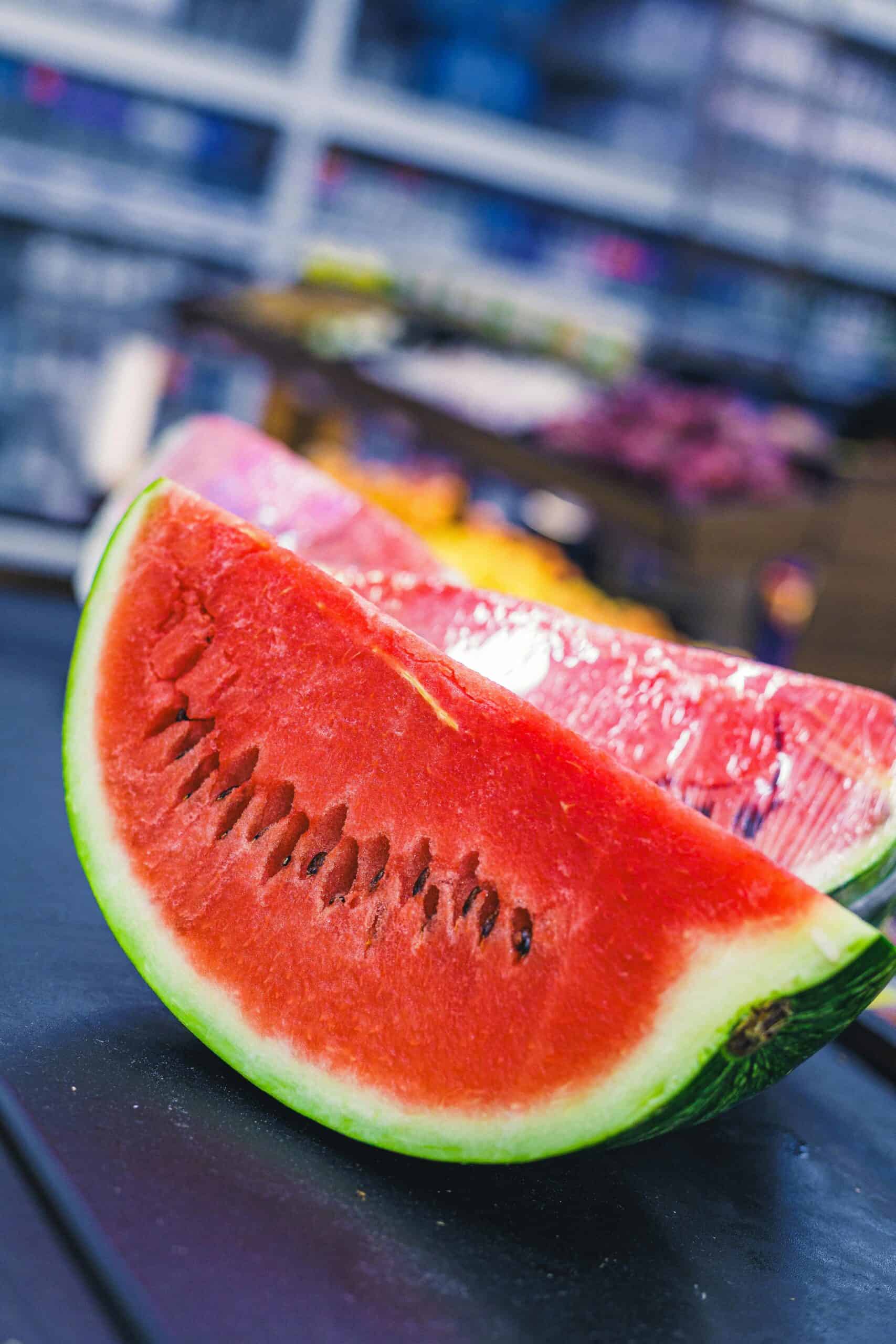 two wedges of watermelon sitting on a wood table